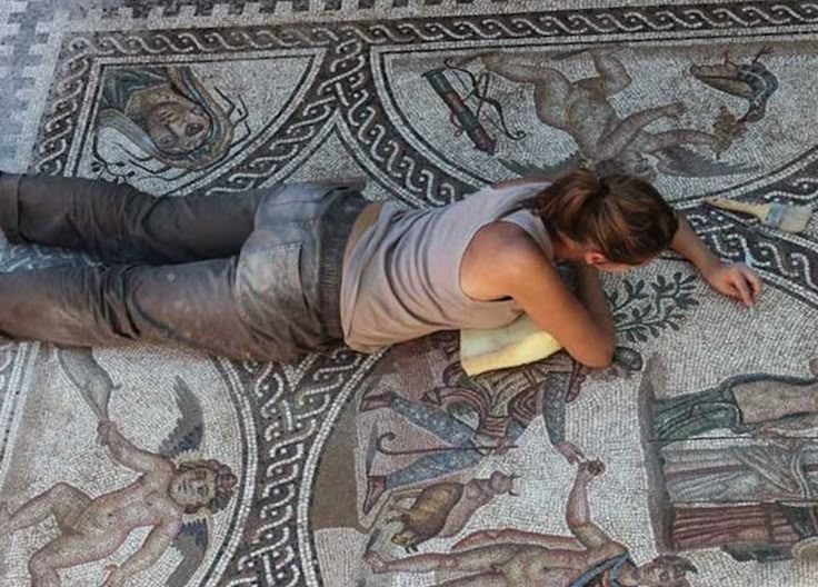 This may contain: a woman laying on the ground next to a mosaic